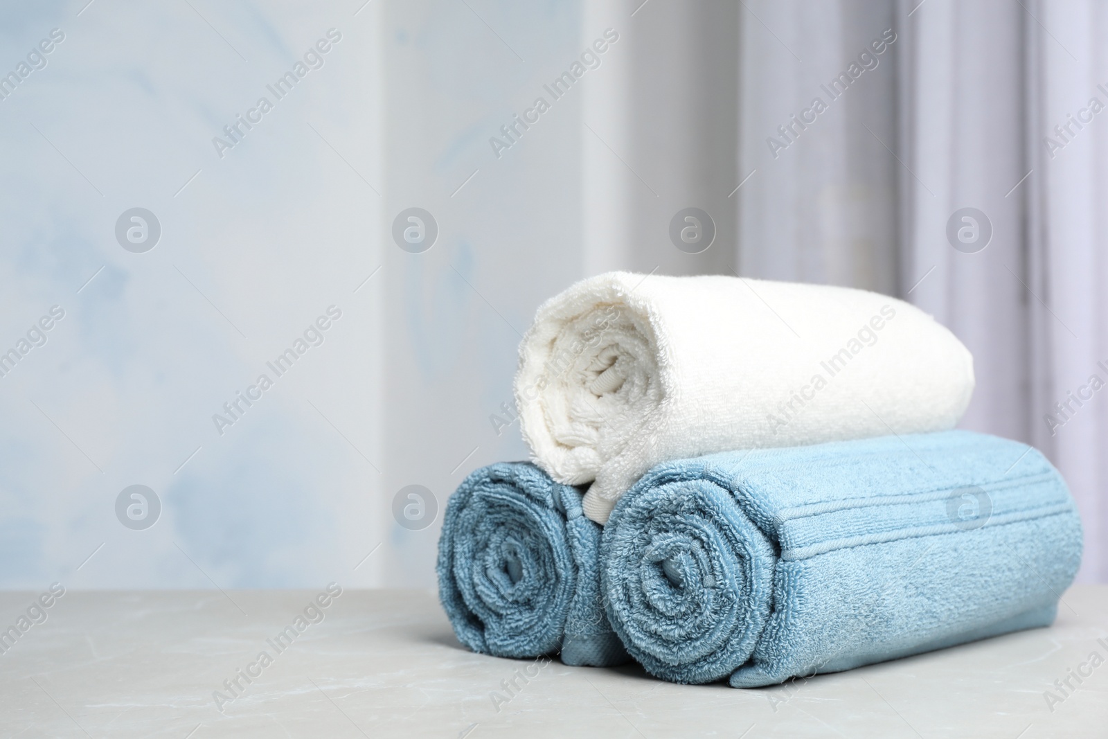 Photo of Rolled bath towels on table against blurred background. Space for text