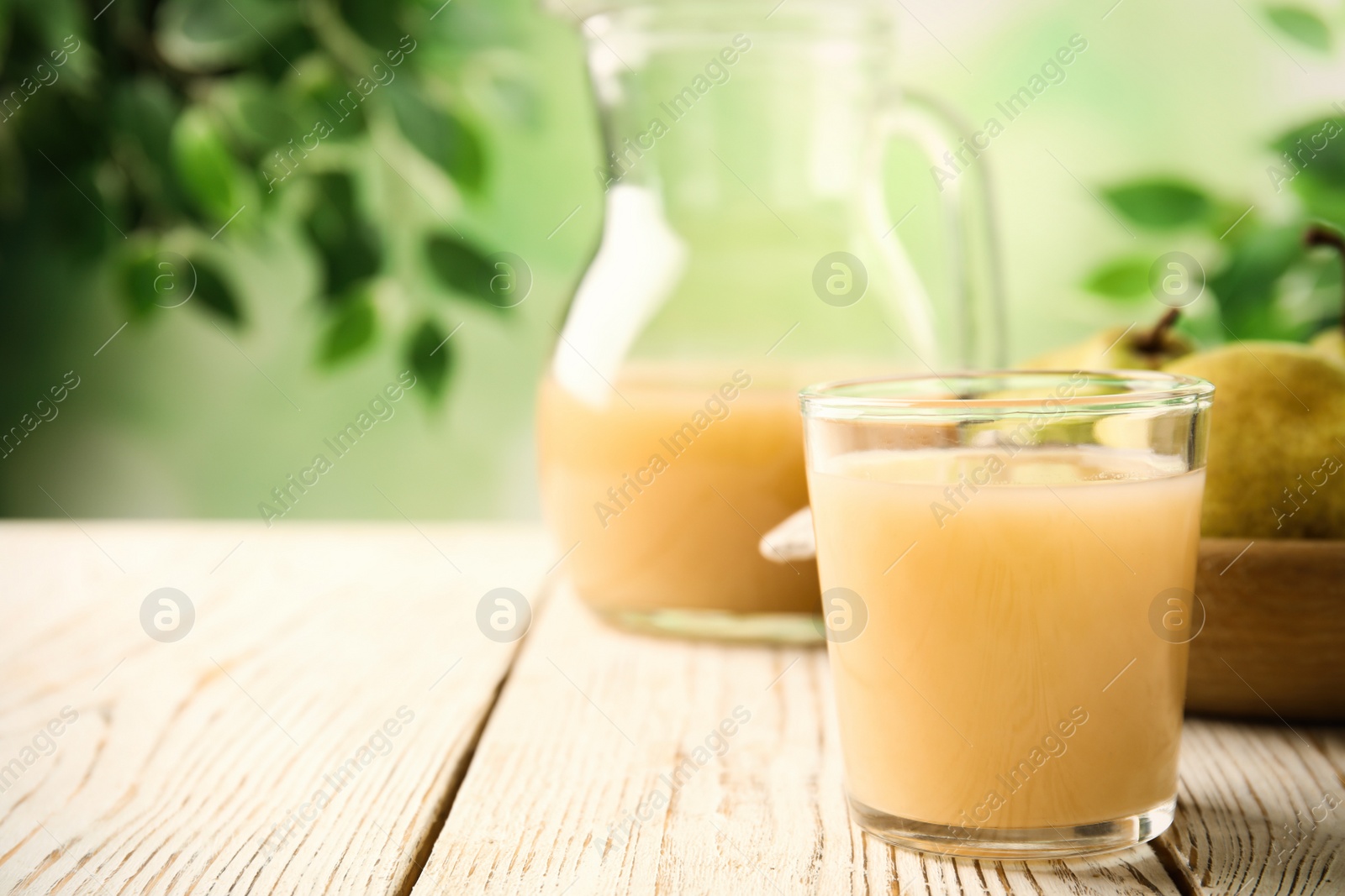 Photo of Fresh pear juice in glass on white wooden table, closeup. Space for text