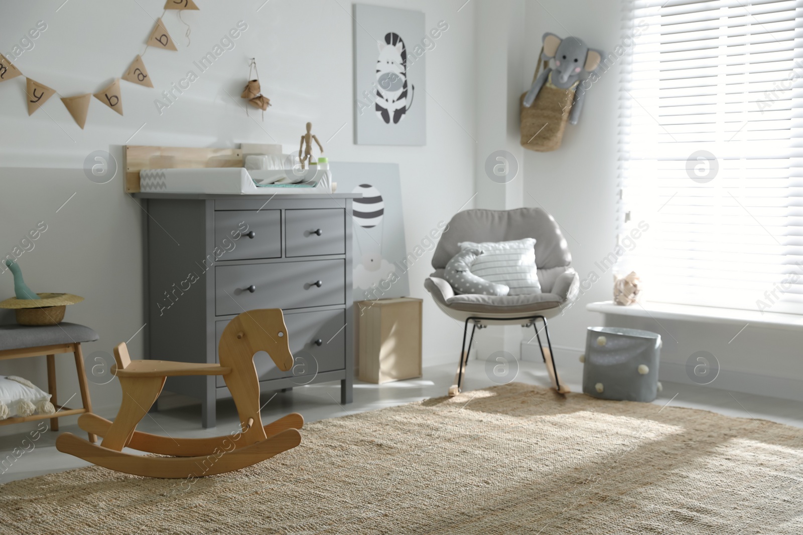 Photo of Beautiful baby room interior with toys, rocking chair and modern changing table