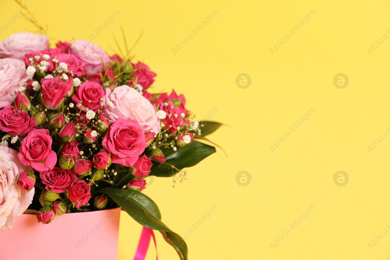 Photo of Beautiful bouquet of flowers in paper gift box on color background. Space for text