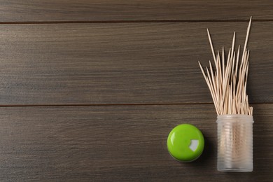 Disposable toothpicks and holder on wooden background, flat lay. Space for text