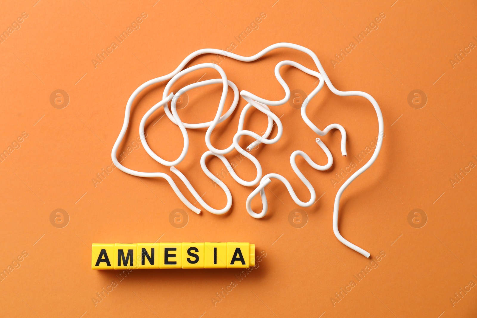 Photo of Word Amnesia and brain made of wires on orange background, flat lay