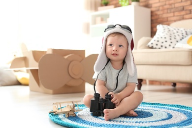 Photo of Adorable little child playing with binoculars at home