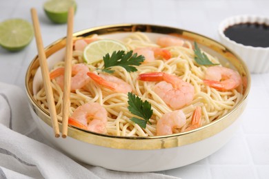 Tasty spaghetti with shrimps and parsley in bowl on white tiled table, closeup