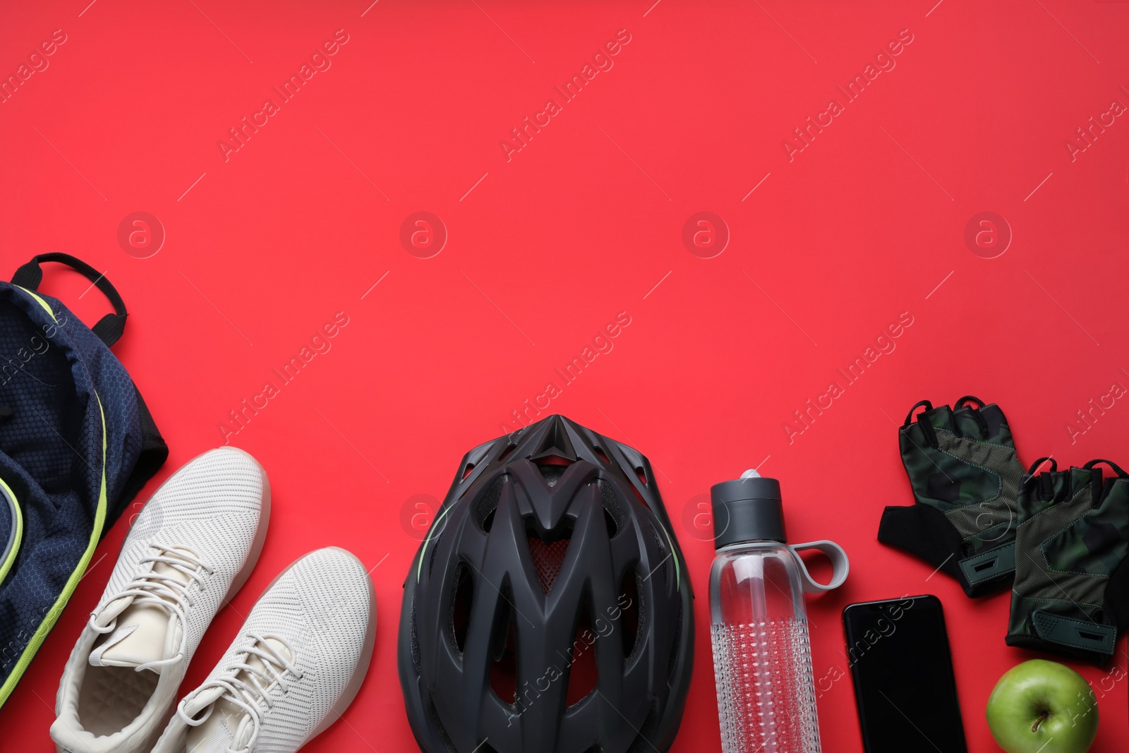 Photo of Flat lay composition with different cycling accessories on red background, space for text