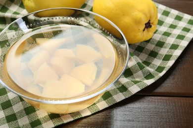 Photo of Delicious quince drink in glass bowl and fresh fruit on wooden table, closeup