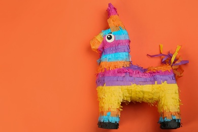 Bright donkey pinata on orange background, top view. Space for text