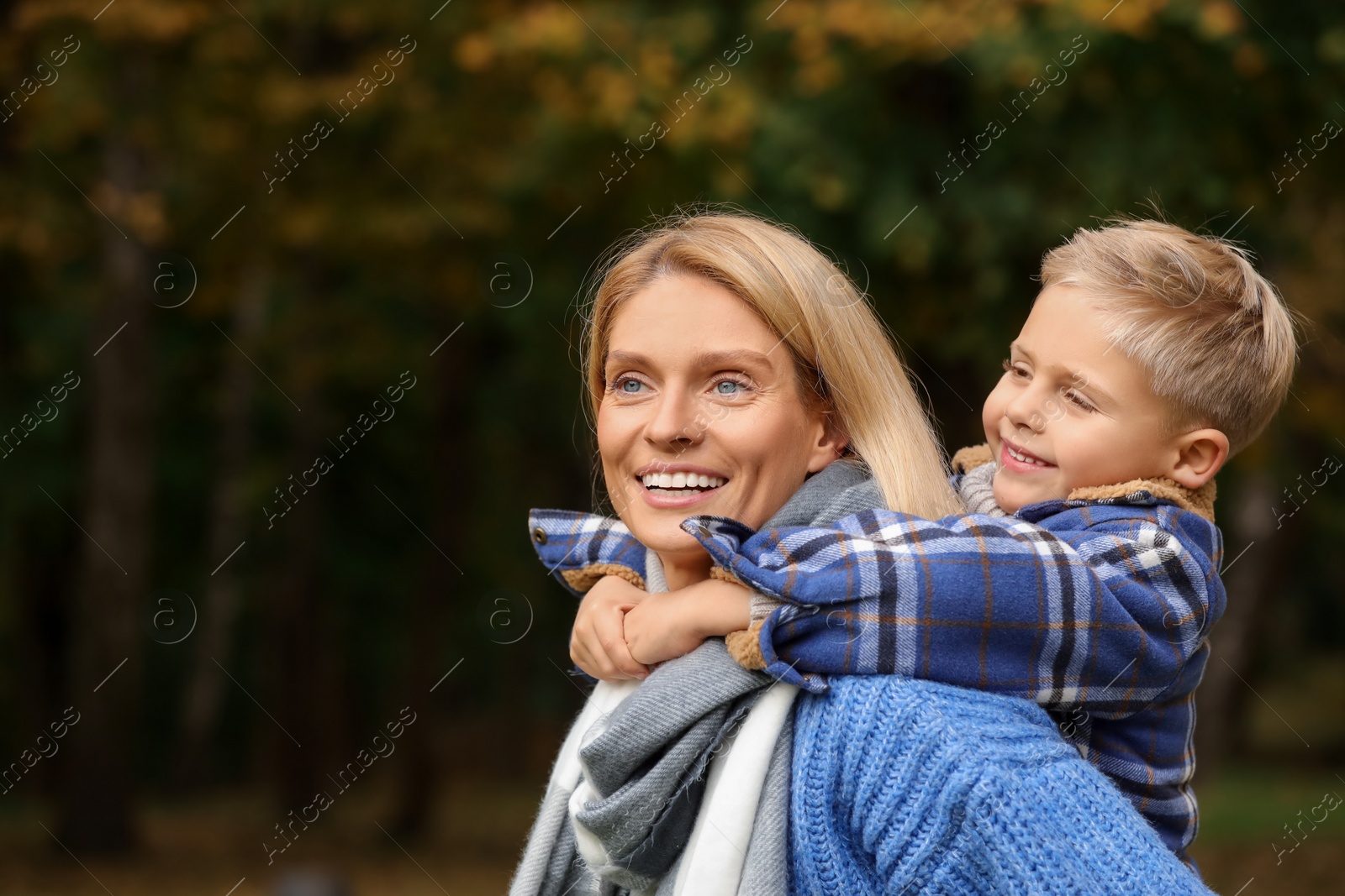 Photo of Happy mother with her son in autumn park. Space for text