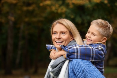 Photo of Happy mother with her son in autumn park. Space for text