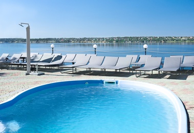 Photo of Swimming pool with clean blue water and lounge chairs outdoors