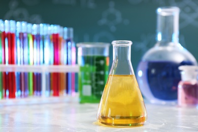 Photo of Conical flask on table against blurred background, space for text. Chemistry glassware