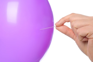 Photo of Woman piercing purple balloon on white background, closeup