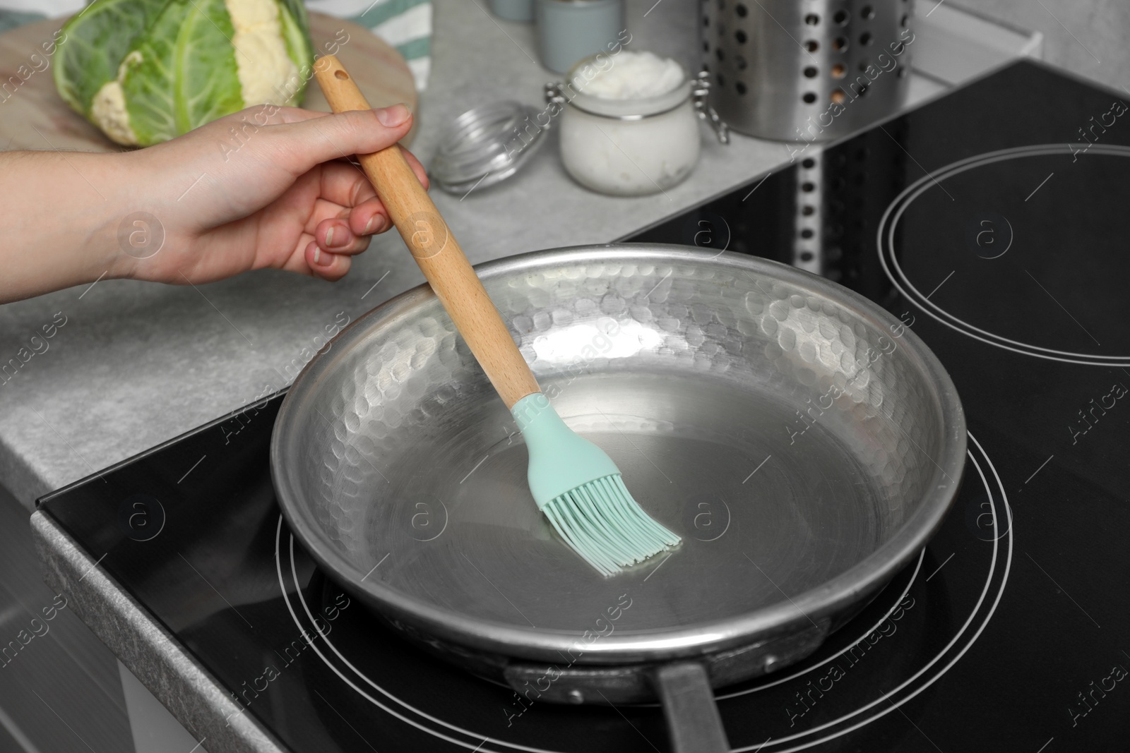 Photo of Woman cooking with coconut oil on induction stove, closeup