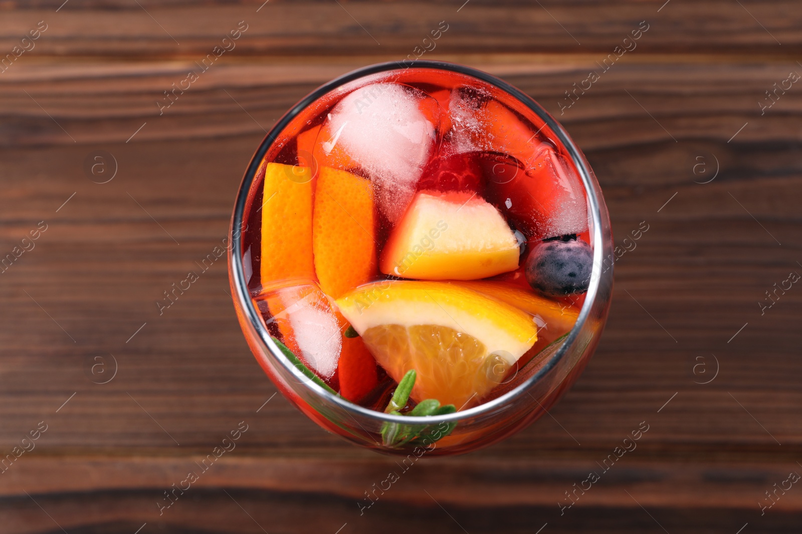 Photo of Glass of delicious sangria on wooden table, top view