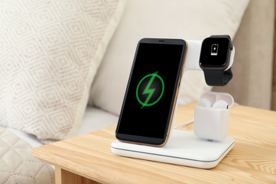 Photo of Different gadgets charging on wireless pad in bedroom