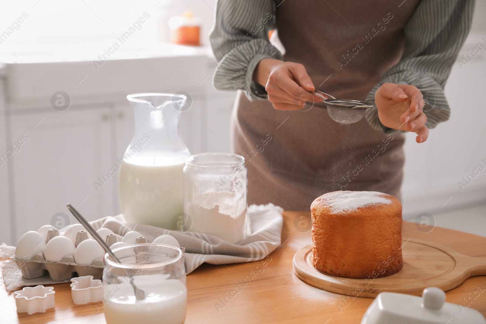 Photo of Young woman making traditional Easter cake in kitchen, closeup