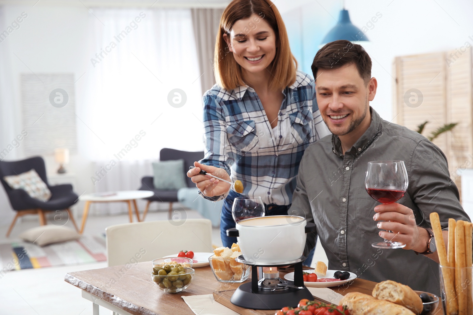 Photo of Happy couple enjoying fondue dinner at home