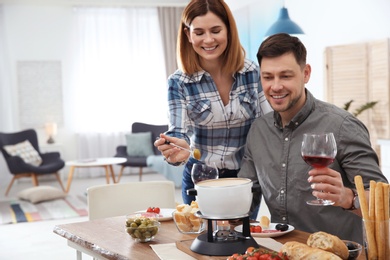 Photo of Happy couple enjoying fondue dinner at home