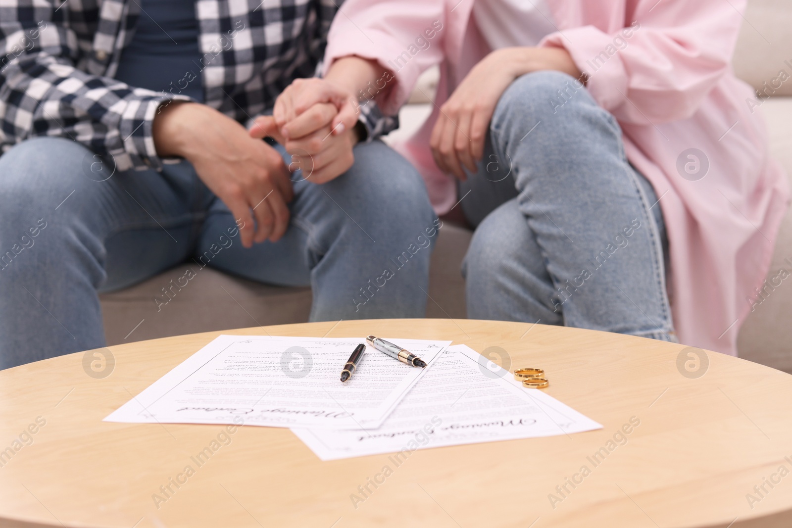 Photo of Man and woman signing marriage contract at wooden table indoors, closeup