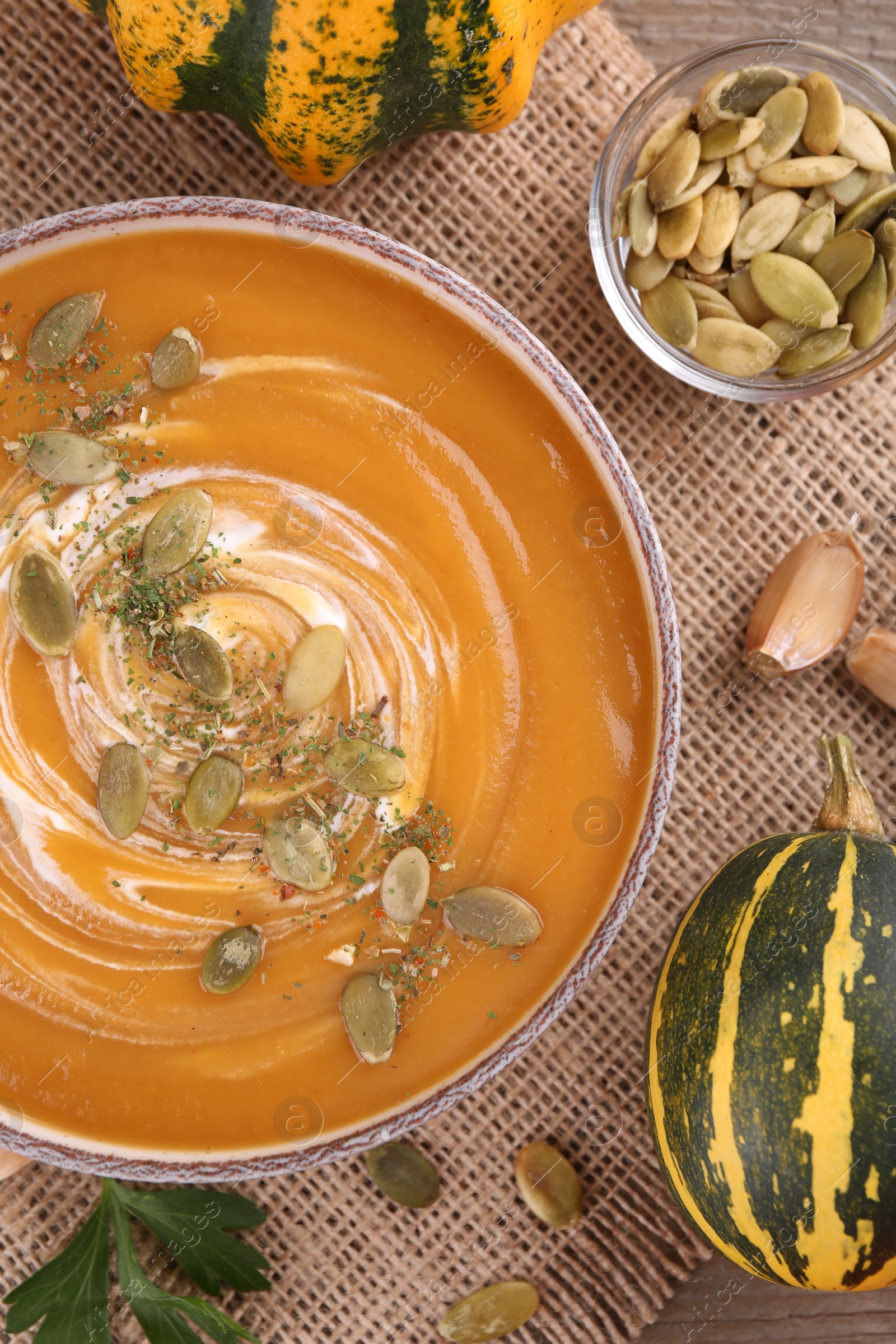 Photo of Flat lay composition with bowl of delicious pumpkin soup on table