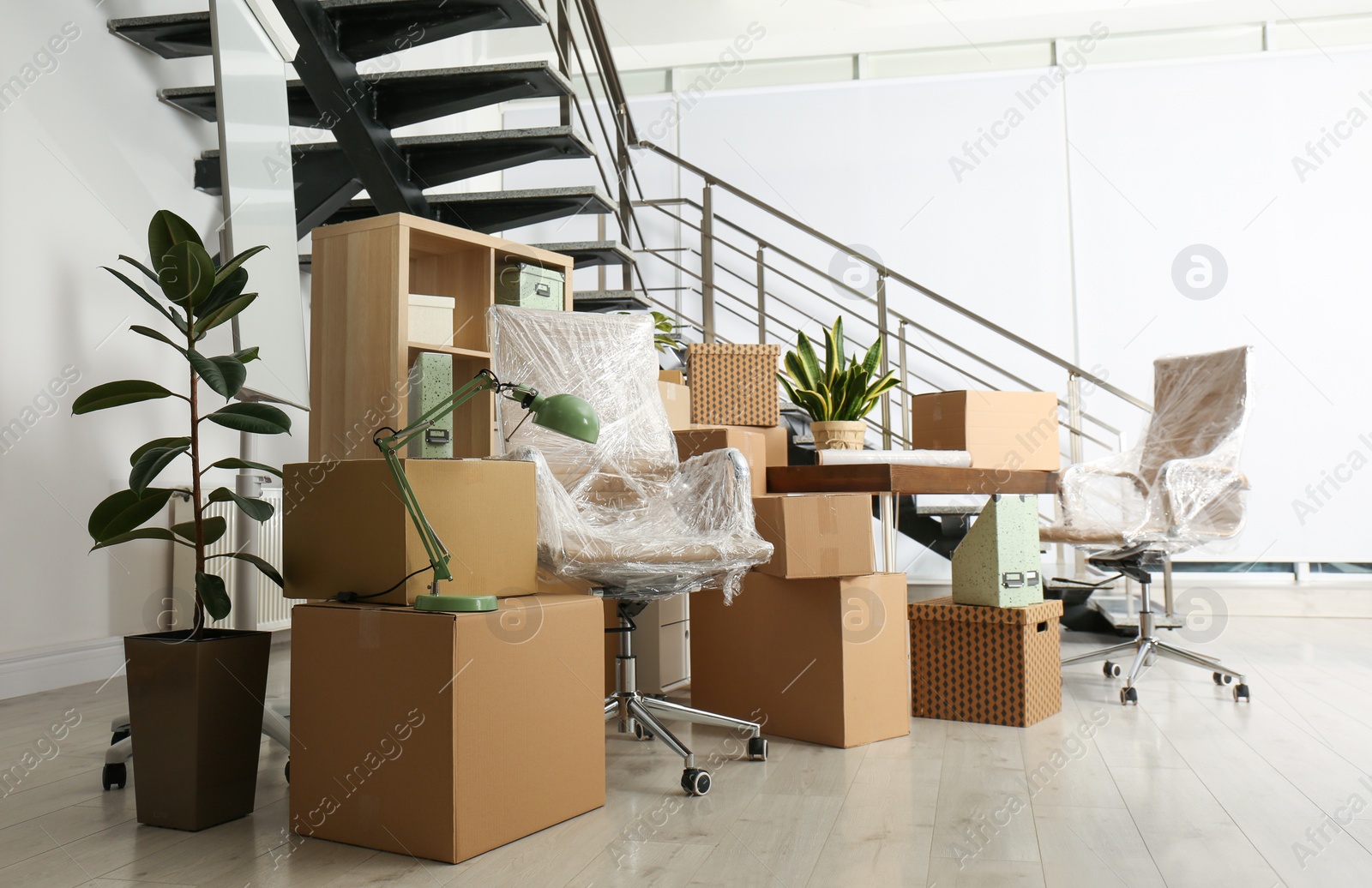 Photo of Cardboard boxes and furniture near stairs in office. Moving day