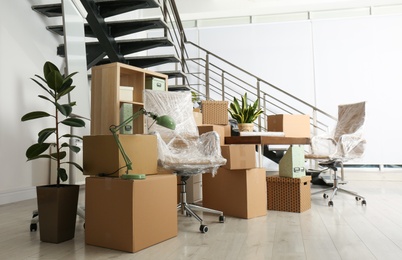 Photo of Cardboard boxes and furniture near stairs in office. Moving day