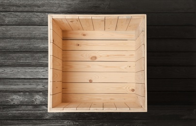 Photo of Open empty wooden crate on black background, top view