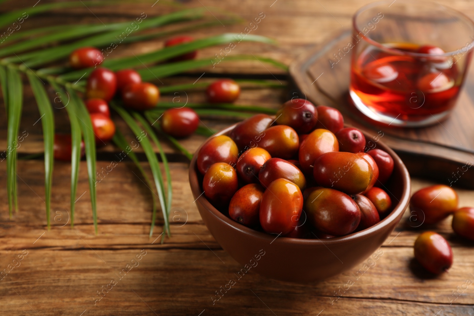 Photo of Palm oil fruits in bowl on wooden table, closeup