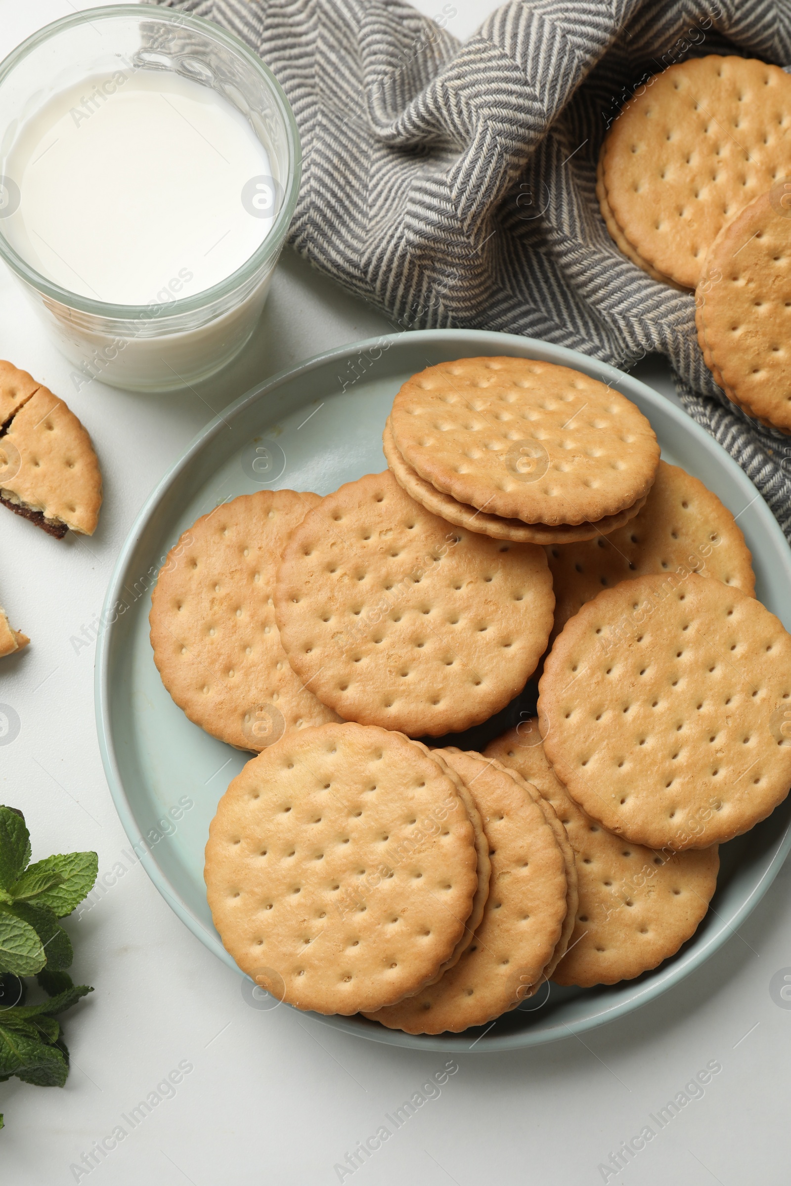 Photo of Tasty sandwich cookies and glass of milk on white table, above view