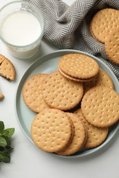 Tasty sandwich cookies and glass of milk on white table, above view