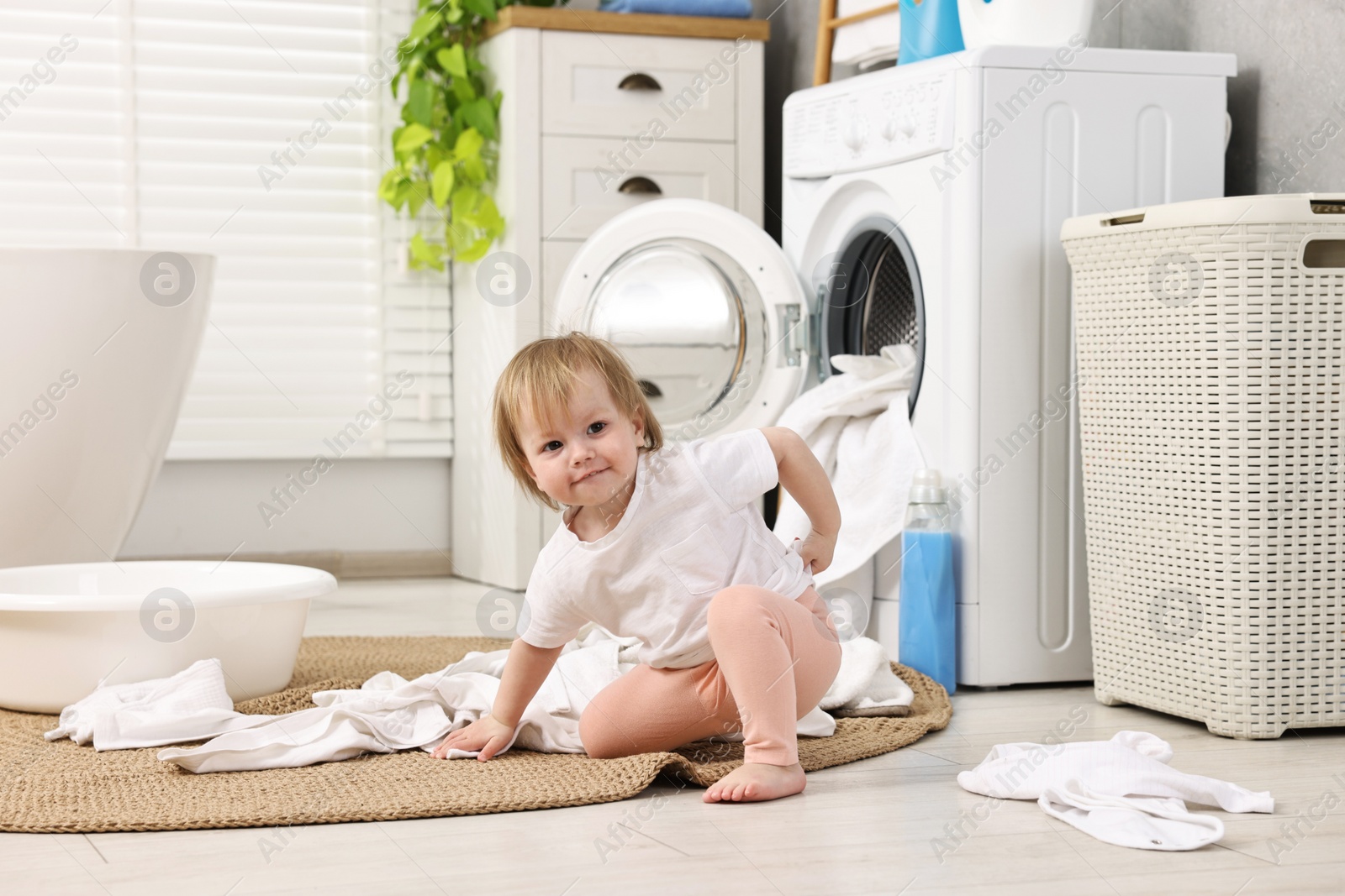 Photo of Little girl and baby clothes in bathroom