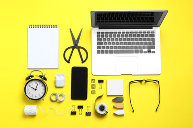 Photo of Flat lay composition with laptop, smartphone and stationery on yellow background. Designer's workplace