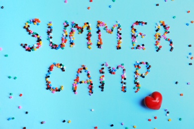 Photo of Flat lay composition with words SUMMER CAMP made from beads on color background