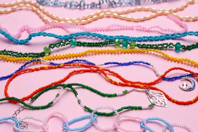 Photo of Beautiful handmade beaded necklaces on pink background