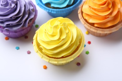 Photo of Many tasty cupcakes with bright cream and sprinkles on white background, above view