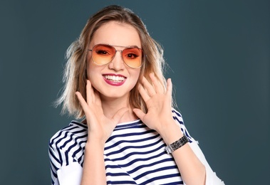 Photo of Beautiful young woman with sunglasses posing on color background