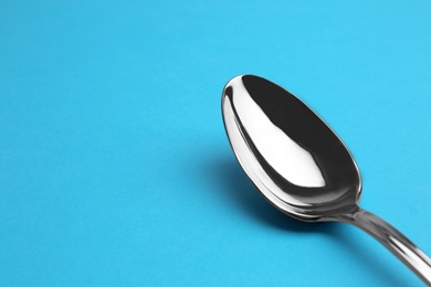 Photo of Clean empty tea spoon on blue background, space for text