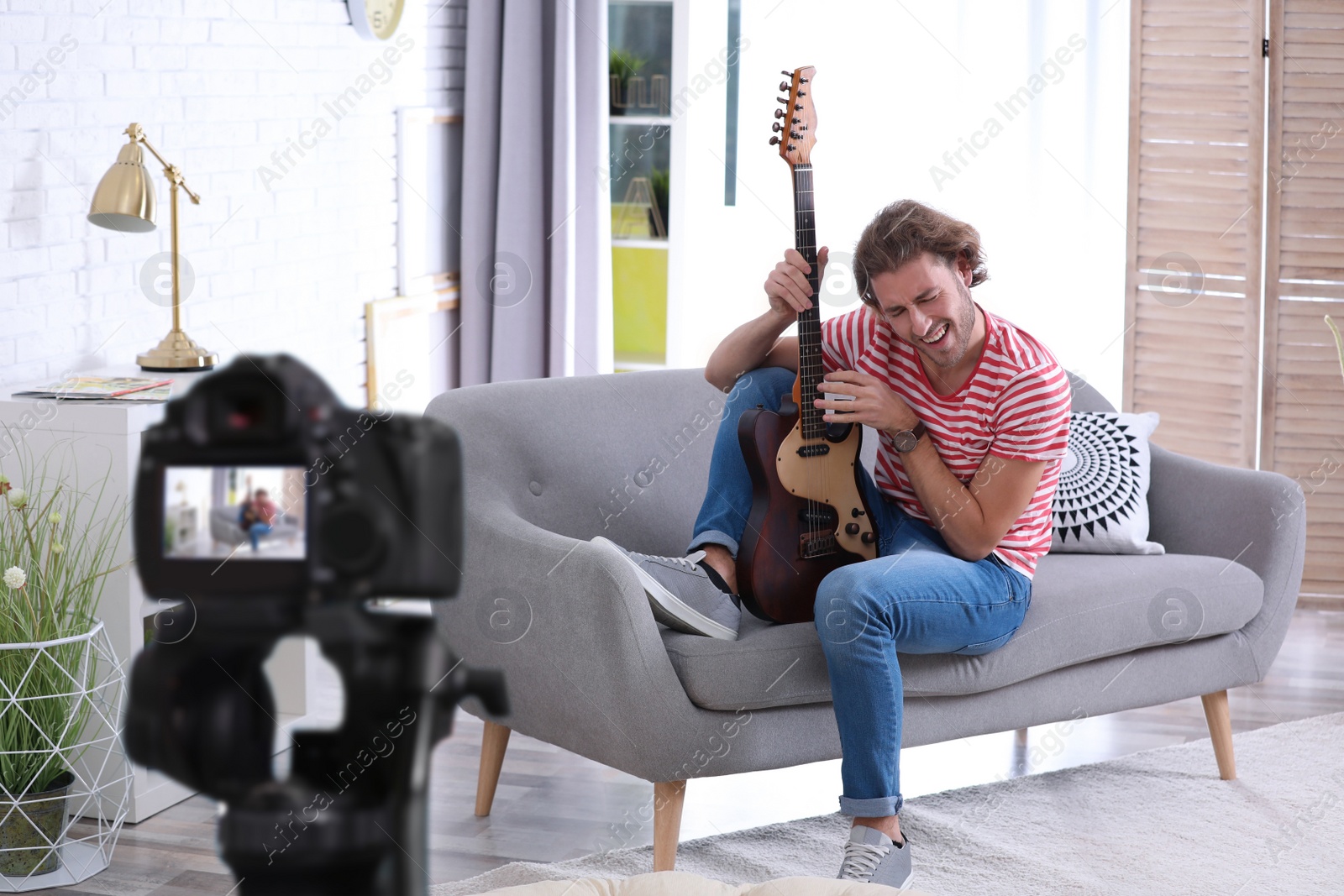 Image of Music teacher recording guitar lesson at home