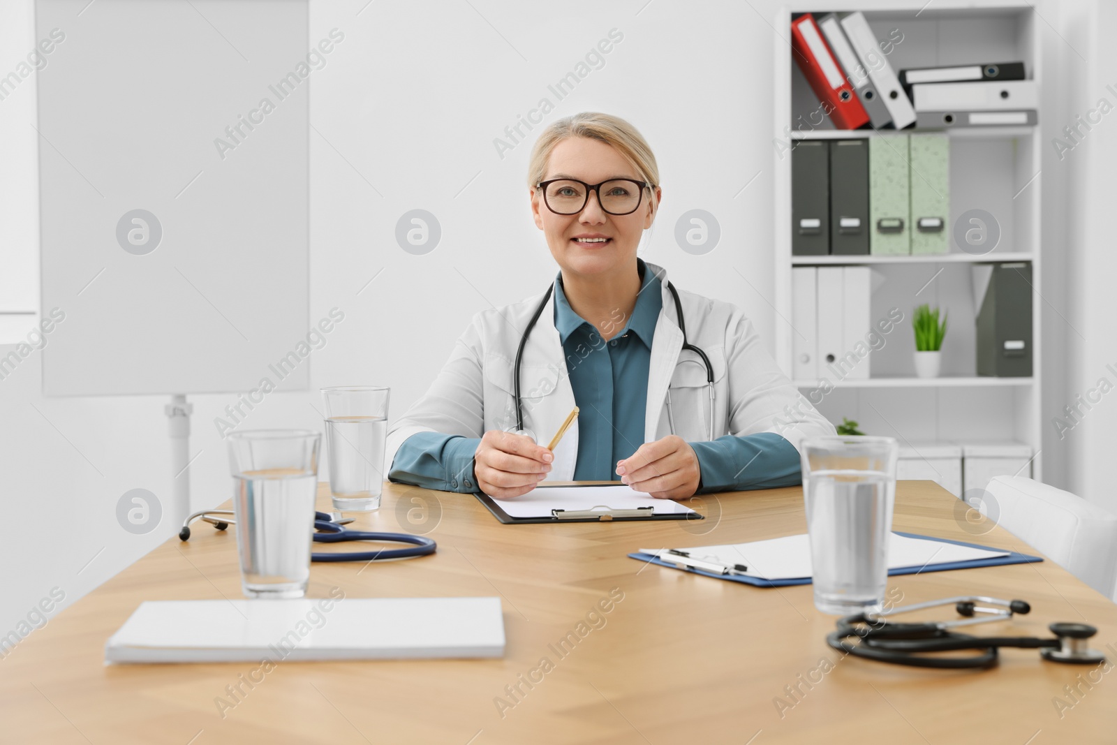 Photo of Professional doctor sitting at wooden table in clinic