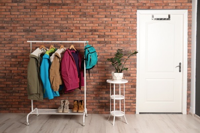 Modern hallway interior with white door and clothes on rack