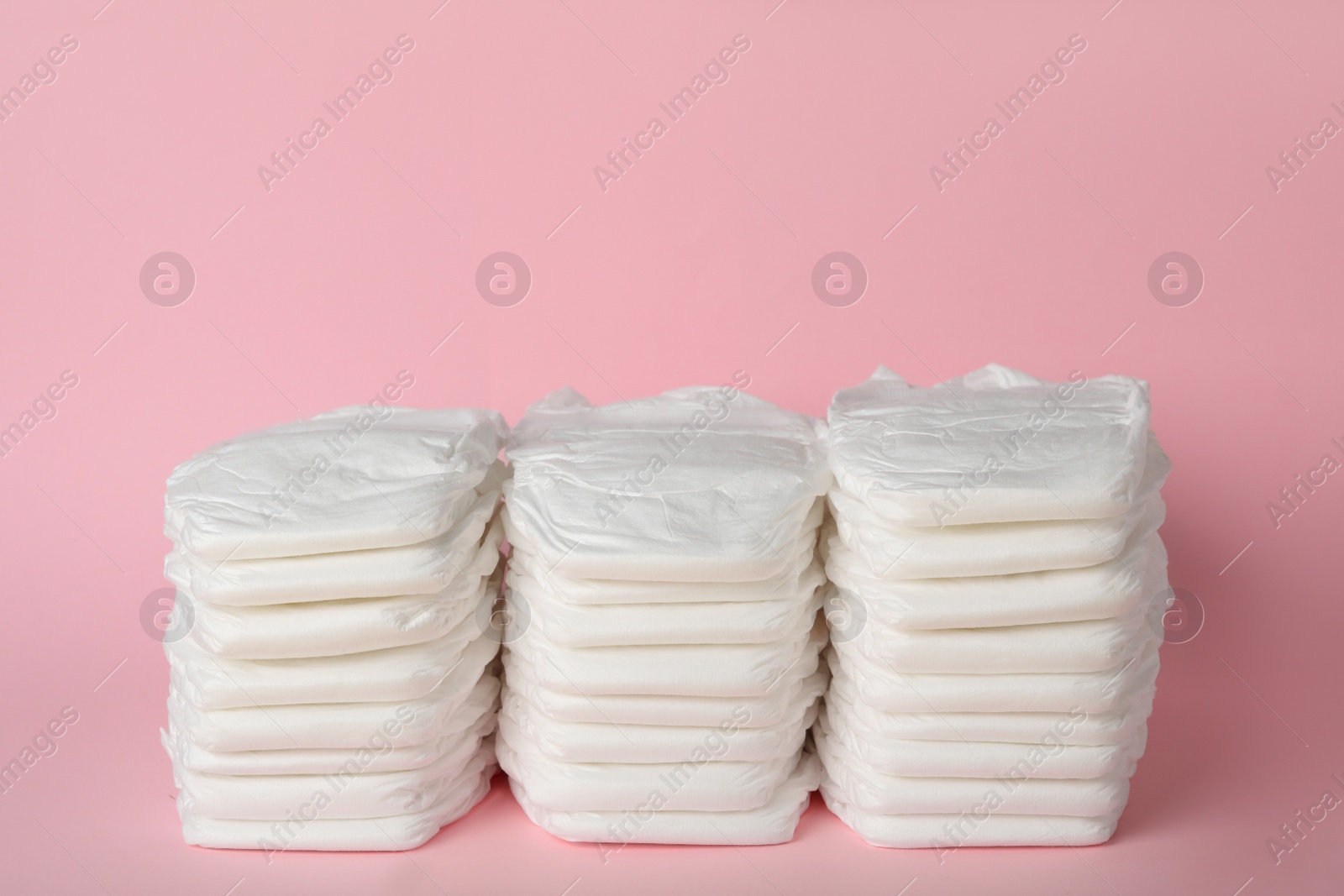 Photo of Stacks of baby diapers on pink background