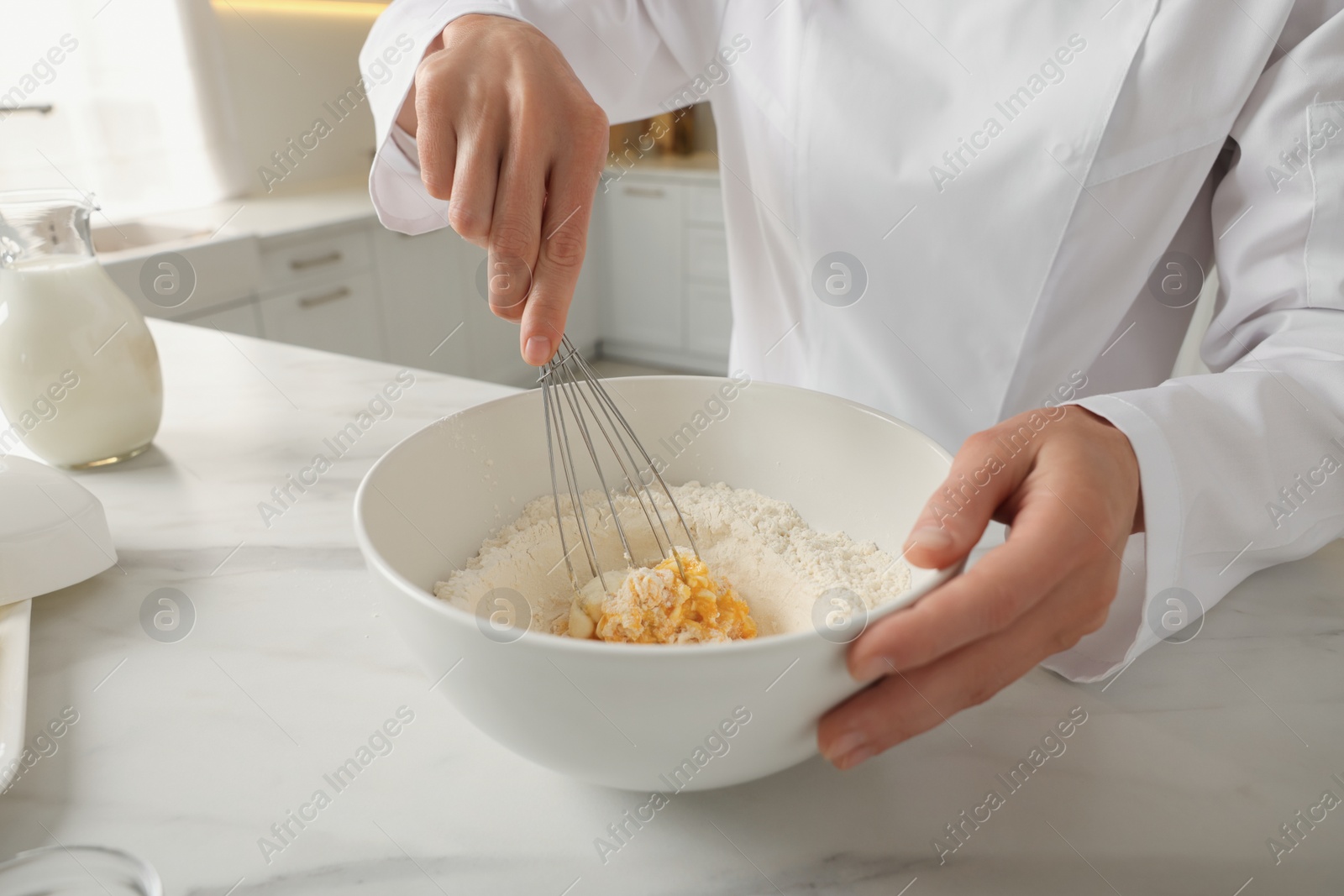 Photo of Professional chef making dough at white marble table indoors, closeup