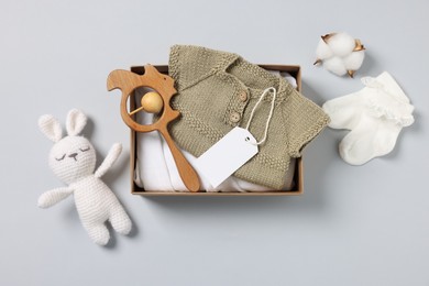 Photo of Different baby accessories, clothes and blank card on light grey background, flat lay