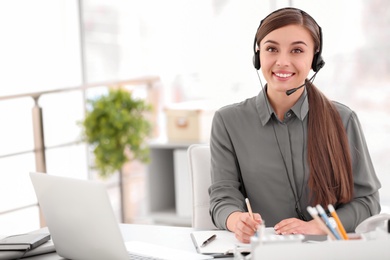 Photo of Young woman talking on phone through headset at workplace