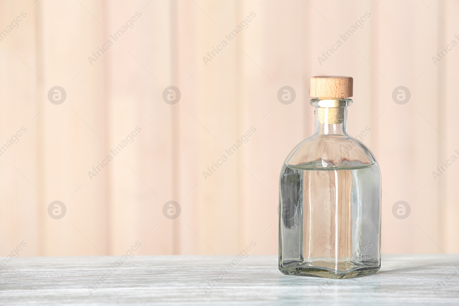 Photo of Glass bottle with vinegar on wooden table. Space for text