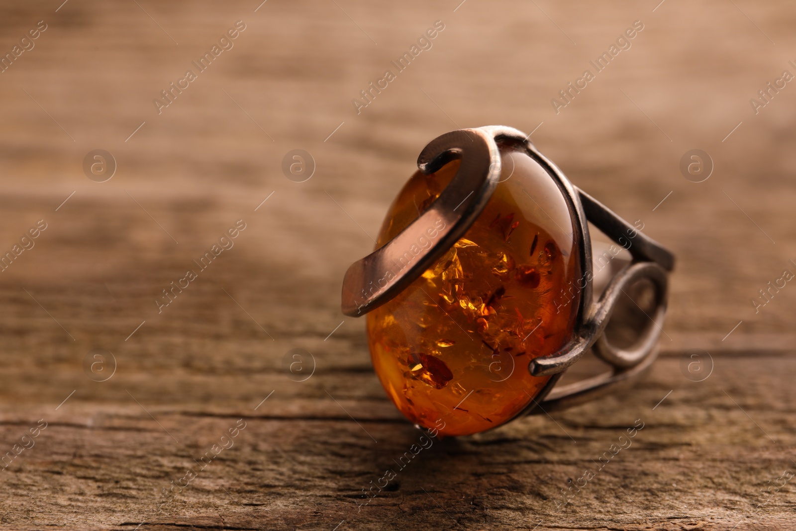 Photo of Beautiful ring with gemstone on wooden surface, closeup. Space for text