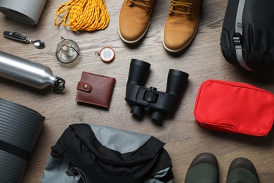 Photo of Flat lay composition with different camping equipment on wooden background