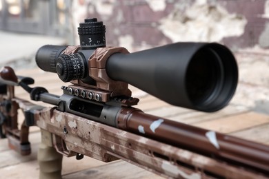 Photo of Closeup view of modern powerful sniper rifle with telescopic sight outdoors