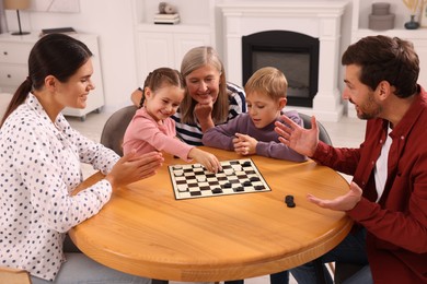 Family playing checkers at wooden table in room