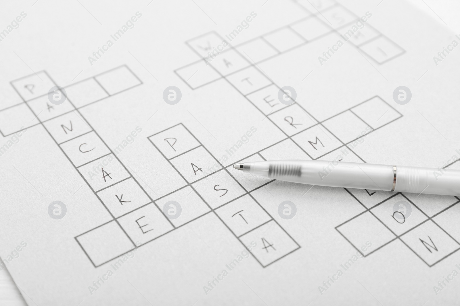 Photo of Crossword with answers and pen, closeup view